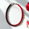 Handmade Crimson Noir Kumihimo beaded necklace with red and black glass seed beads styled with roses on white background